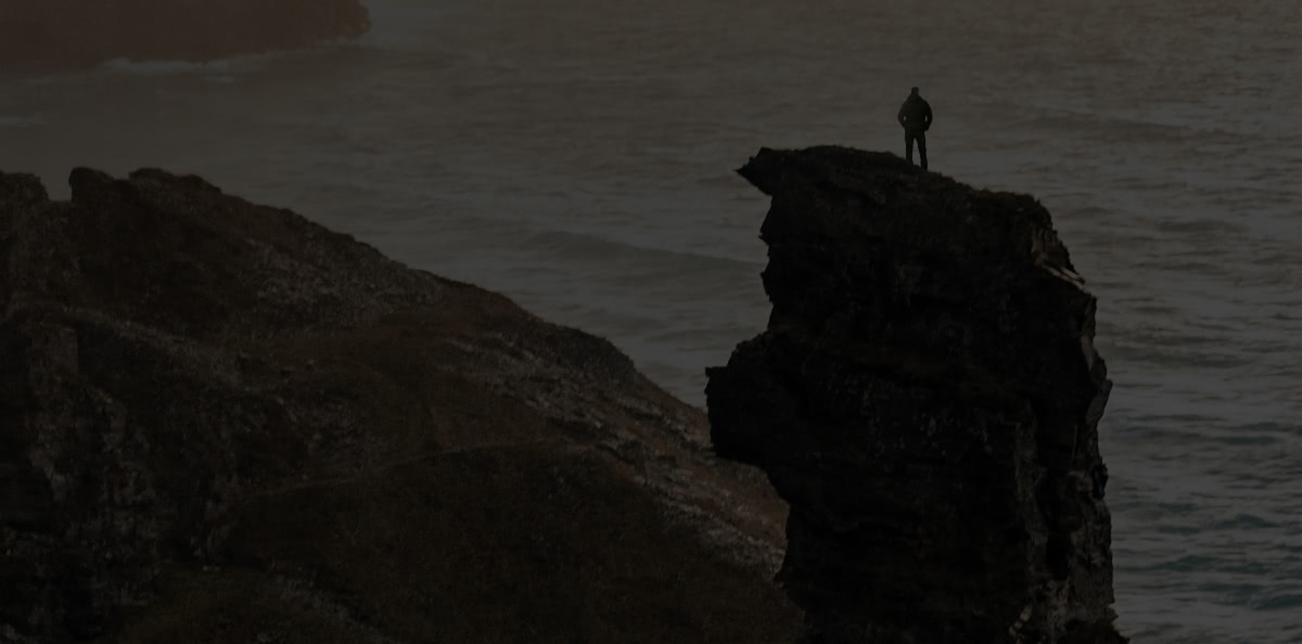 Background image of a person standing on a cliff top.